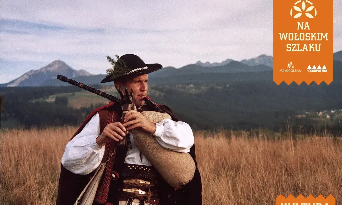 Muzykant w tradycyjnym stroju góralskim gra na dudach, prezentując żywy folklor góralski na tle malowniczych Tatr.