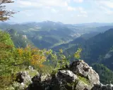 Widok z bacówki Trzy Korony na malowniczą dolinę Pienin. W oddali widać góry i lasy.