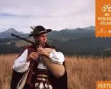 Muzykant w tradycyjnym stroju góralskim gra na dudach, prezentując żywy folklor góralski na tle malowniczych Tatr.