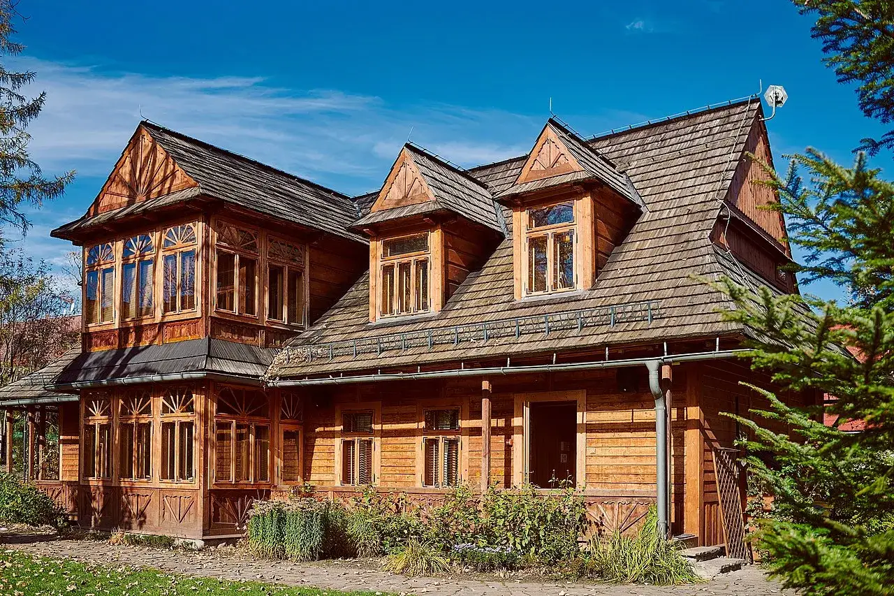 Drewniana willa w stylu zakopiańskim, z charakterystyczną zakopiańską architekturą, okiennicami i gontowym dachem.